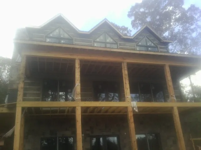 Dormers and porch framing on a large log home under construction — Roof Coating work by our crew in Castle Rock