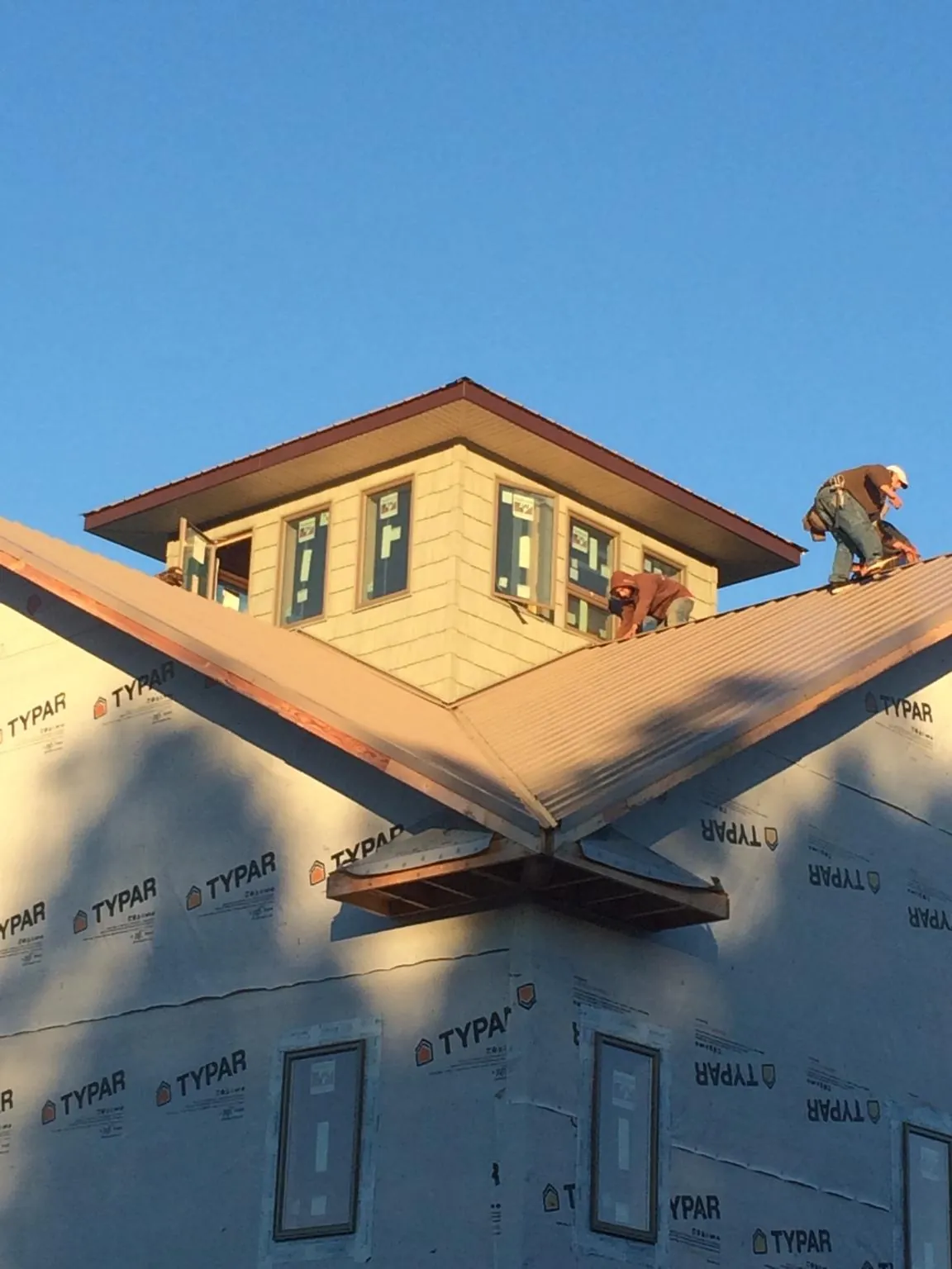 Roofers working around a rooftop cupola on a new metal roof at sunset — Roof Waterproofing in Castle Rock by Roofing Brothers